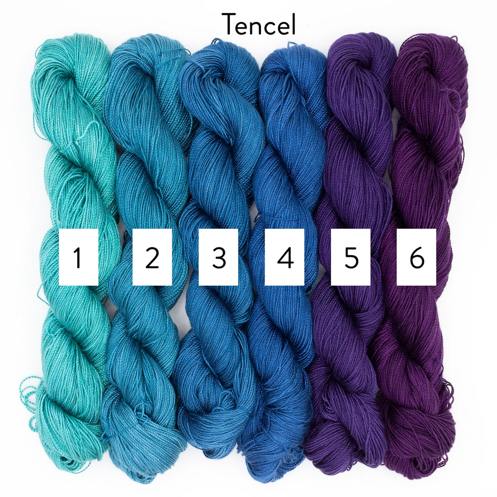 Six skeins of Tencel yarn in teal, blue, and purple on a white background